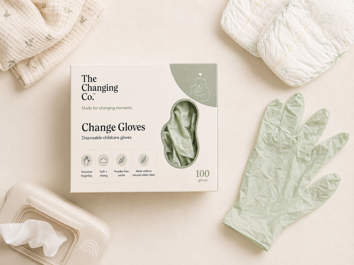 Change Gloves box and an unfolded sage glove arranged with baby-care essentials